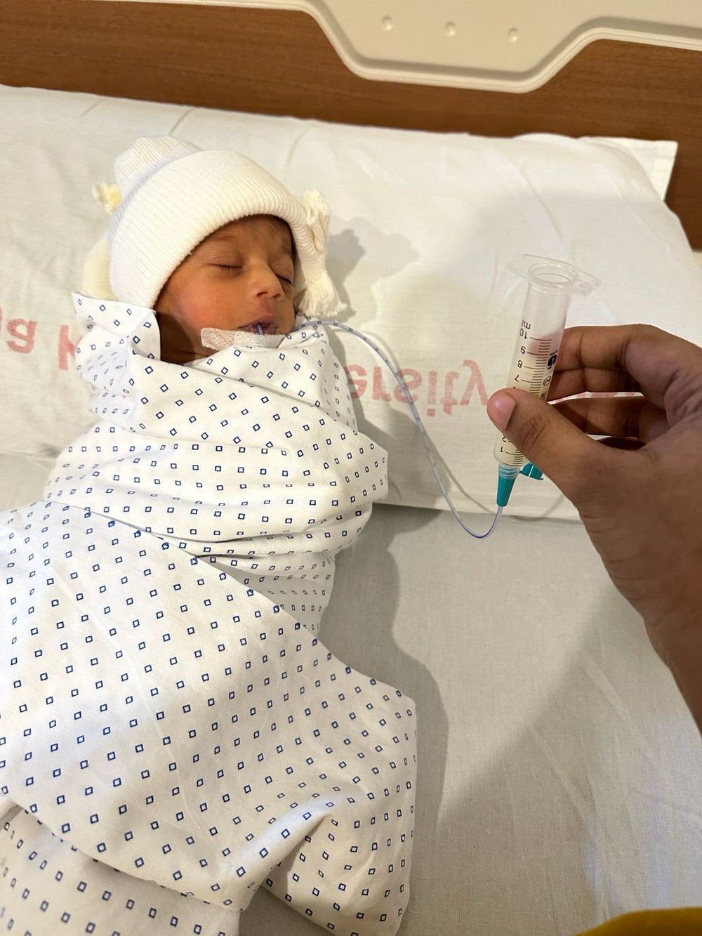 Premature baby holding parent's finger